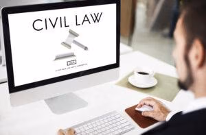A man is sitting in front of a laptop computer with the words Civil Law showing up on the computer screen.